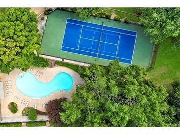Stunning aerial view showcases a blue tennis court and sparkling pool surrounded by lush green trees at 13 Ivy Ne Sq, Atlanta, GA 30342