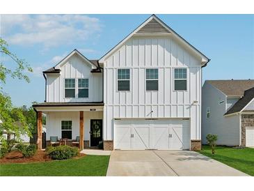 Charming two-story white farmhouse with a well-manicured lawn and a two-car garage at 701 Woodward Ct, Canton, GA 30114
