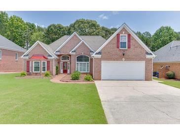 Charming brick home featuring a manicured lawn, two-car garage, and tasteful landscaping at 1125 Lewis Ridge Cir, Lawrenceville, GA 30045