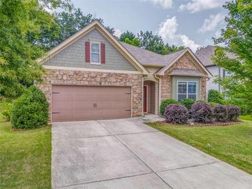 Charming home featuring a stone facade, two-car garage, manicured lawn, and meticulously maintained landscaping at 105 Silver Trce, Dallas, GA 30157