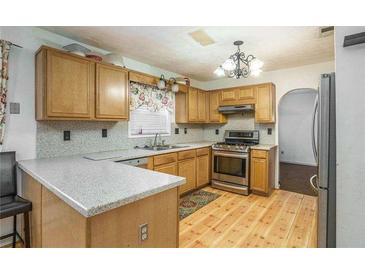 Well-lit kitchen features wood cabinets, wood floors, a gas range and a granite countertop on the breakfast bar at 493 Whaleys Lake Dr, Jonesboro, GA 30238