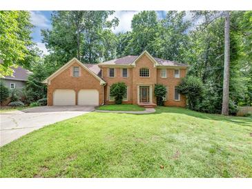 Stately brick home featuring a two-car garage and lush green lawn at 11575 Wildwood Springs Dr, Roswell, GA 30075