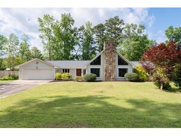 Ranch-style house with a stone chimney, a two-car garage and well-manicured lawn and mature landscaping at 297 Northgate Trce, Roswell, GA 30075