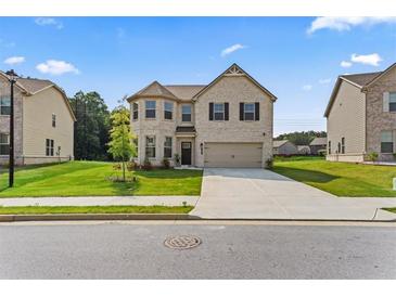 Charming two-story brick home featuring a manicured lawn and a two-car attached garage at 49 Ryder Pass Way, Loganville, GA 30052