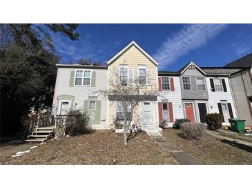 View of the townhome's front exterior featuring varying paint colors and some landscaping at 497 Prince Of Wales, Stone Mountain, GA 30083