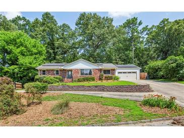 Charming brick home with a lush front yard, mature trees and solar panels on the roof at 3292 Ferncliff Ne Pl, Atlanta, GA 30324
