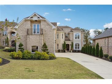 Stately brick home featuring manicured landscaping and a long, paved driveway on a sunny day at 3423 Jamont Blvd, Alpharetta, GA 30022