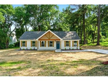 Charming single-story home with board and batten siding, gable pediment, and a lush green lawn at 124 Sims Dr, Hiram, GA 30141