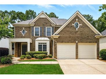 Traditional two-story brick home featuring a two-car garage, symmetrical design and manicured landscaping at 12554 Huntington Trce, Alpharetta, GA 30005