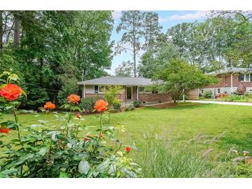 Charming single-story brick home with a lush green lawn and colorful flowers in the landscaped front yard at 2889 Mount Olive Dr, Decatur, GA 30033