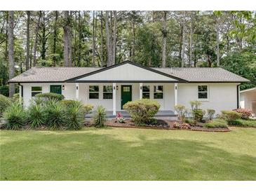 Charming single-story home with white brick, a green door, and a well-manicured lawn and flower bed at 1891 Sahara Se Dr, Atlanta, GA 30316