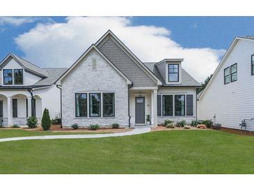 Charming single-Gathering home featuring a stone facade, manicured lawn, and black trimmed windows at 158 South Village Ave, Holly Springs, GA 30115