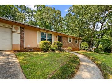 Charming single-story home with a well-manicured lawn, mature trees and curved sidewalk at 1594 Pine Glen Cir, Decatur, GA 30035