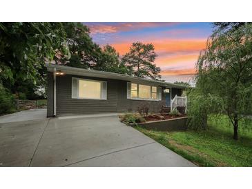 Charming single-story home with concrete driveway, blue front door and manicured landscaping at 1977 Wee Kirk Se Rd, Atlanta, GA 30316