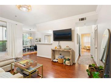 Bright living room features hardwood floors, a large television, and a view into dining area at 3777 Peachtree Ne Rd # 1112, Brookhaven, GA 30319