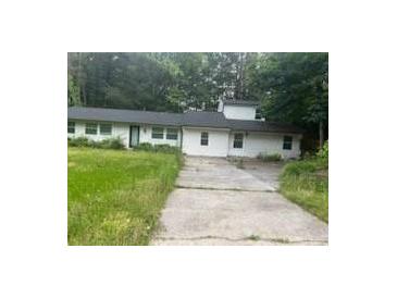 Ranch-style home features a long, single-story layout with a concrete driveway surrounded by trees at 3785 Somerset Sw Dr, Marietta, GA 30064