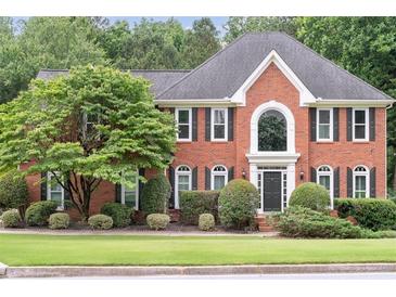 Charming brick two-story home with manicured lawn and mature trees showcasing classic curb appeal at 9310 Chapelwood Dr, Johns Creek, GA 30022