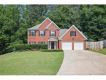 Charming brick home featuring a well-manicured lawn, mature trees, and a two-car garage at 206 Five Iron Nw Ct, Kennesaw, GA 30144