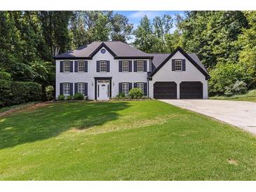Traditional two-story house with brick facade, black shutters, a well manicured lawn and a two car garage at 4220 Singing Post Ne Ln, Roswell, GA 30075