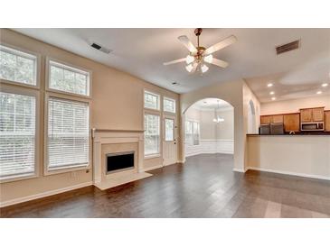 Bright living room featuring hardwood floors, fireplace, and large windows with a view to the kitchen at 2280 Copper Trail Ln, Buford, GA 30519