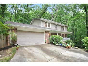 Charming two-story home featuring an attached garage, front porch, brick facade, and lush green landscaping at 3025 Mountain Creek Ne Ct, Roswell, GA 30075