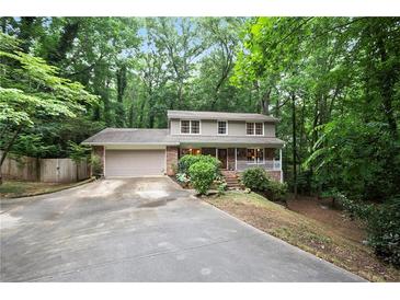 Charming two-story home with a front porch and a spacious driveway surrounded by lush greenery at 3025 Mountain Creek Ne Ct, Roswell, GA 30075