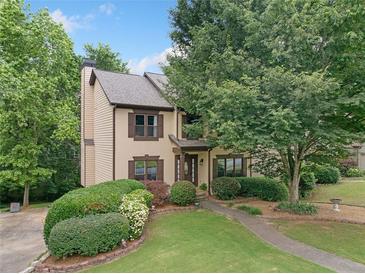 Stucco and wood facade is surrounded by mature trees and has manicured landscaping at 404 Pine Grove Way, Woodstock, GA 30189