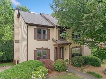 Charming two-story home with a stucco facade, brown trim, and mature landscaping at 404 Pine Grove Way, Woodstock, GA 30189