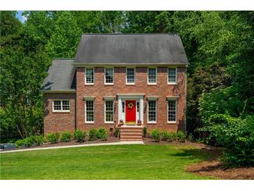 Charming two-story brick home featuring a bright red front door and a well-manicured lawn at 1885 N Creek Cir, Alpharetta, GA 30009