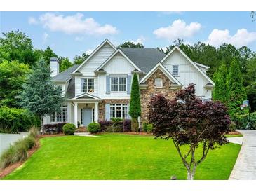 Charming two-story home with stone accents, beautiful landscaping, and a well-manicured lawn at 5963 Wild River Vw, Sugar Hill, GA 30518