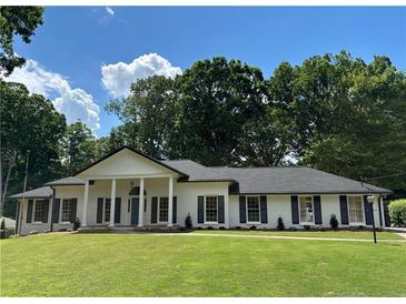 Charming single story home with white brick, black shutters and beautifully manicured lawn at 5631 Queensborough Dr, Atlanta, GA 30338