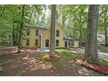 Charming yellow two-story home surrounded by mature trees and landscaping at 7156 Whitfield Drive Dr, Riverdale, GA 30296