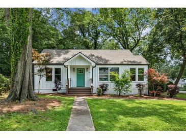 Charming home featuring a manicured lawn, light-colored facade, and inviting front porch with a bright teal front door at 2485 Hillside Ave, Decatur, GA 30032