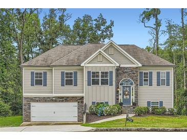 Charming two-story home featuring stone accents, blue shutters, manicured lawn, and a welcoming arched entryway at 79 Little Creek Manor Dr, Dallas, GA 30157