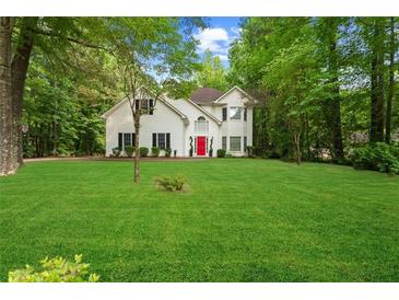 Inviting two-story home with a lush front lawn and a charming red front door at 76 Barrington Farms Pkwy, Sharpsburg, GA 30277