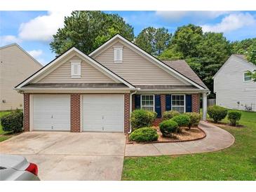 Charming single Gathering home featuring a two-car garage, manicured lawn, and brick accents at 11581 Kades Trl, Hampton, GA 30228