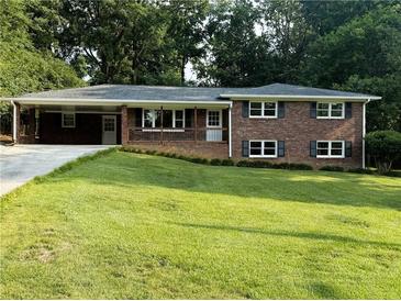 Charming brick home featuring a well-manicured lawn, covered porch, and mature trees at 1850 Donald Dr, Marietta, GA 30062
