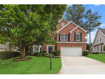 Charming brick home featuring a well-manicured front yard, mature trees, and a two-car garage at 3242 Monarch Pine Dr, Peachtree Corners, GA 30071