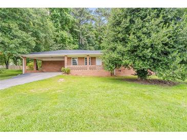 Charming one-story brick home with a well-maintained lawn and mature trees providing ample shade at 4447 Ben Hill Rd, Lithia Springs, GA 30122