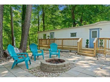 Cozy backyard space with paver patio, fire pit, Adirondack chairs, and a deck on a white home at 1000 Delta Dr, Canton, GA 30114
