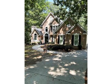 Charming home featuring a curved driveway leading to a traditional facade with meticulously manicured landscaping at 2901 Briscoe Rd, Loganville, GA 30052