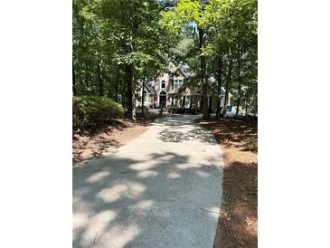Traditional two-story home boasts a lush green lawn and a long driveway, nestled in a mature wooded setting at 2901 Briscoe Rd, Loganville, GA 30052