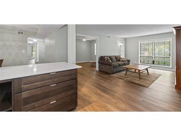 Bright living room features wood floors, area rug, sofa, and updated kitchen bar area at 6851 Roswell Rd # H18, Atlanta, GA 30328