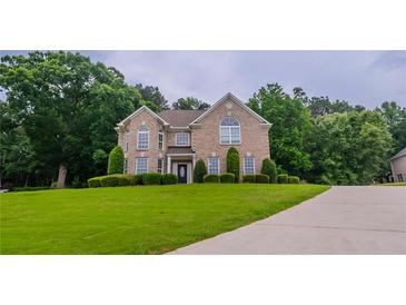 Charming two-story brick home with a well-manicured lawn and mature trees at 157 Hambrick Dr, Stockbridge, GA 30281