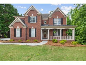 Stately brick home featuring a covered front porch and well-manicured lawn at 2525 Millwater Xing, Dacula, GA 30019