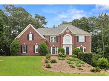 Charming two-story brick home boasts manicured landscaping and lush trees at 340 Old York Rd, Johns Creek, GA 30097