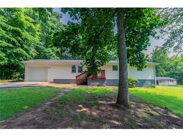Traditional-style home with a lush front yard and a charming red porch, blending into the green surroundings at 6293 Silver Creek Ln, Austell, GA 30168