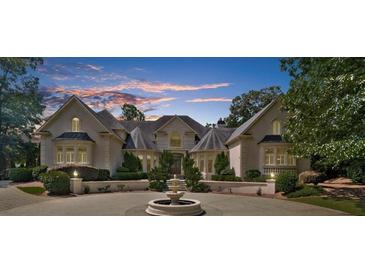 An elegant exterior view of a two-story home featuring a circular driveway and a decorative fountain at 9005 Old Southwick Pass, Alpharetta, GA 30022