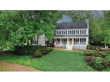 Charming two-story home featuring a welcoming front porch, white siding, black shutters and lush landscaping at 201 Tweed Ct, Sugar Hill, GA 30518