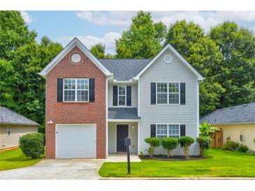 Charming two-story home features a well-manicured lawn, a brick facade, and complementary neutral siding at 7006 Mahonia Place, Stonecrest, GA 30038